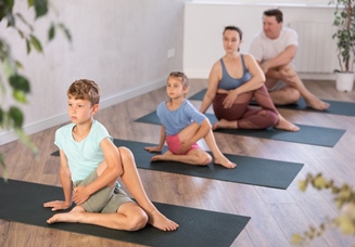 Familia completa haciendo ejercicio de yoga de torsion de espina dorsal